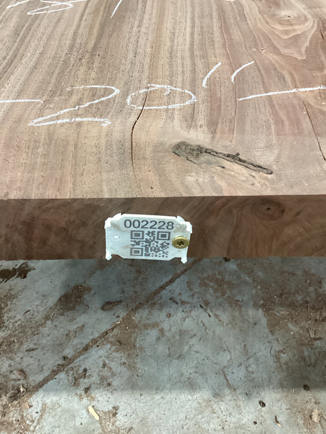 A walnut slab with a unique figure and natural edges, displaying a tag with a QR code and measurements.