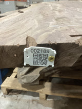 A medium sized walnut slab with visible checking, mounted on a wooden support structure, marked with a numeric code and a QR code.