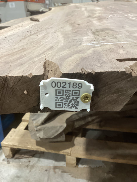 A medium sized walnut slab with visible checking, mounted on a wooden support structure, marked with a numeric code and a QR code.