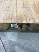 The edge of a beige-colored oak wood slab with visible sku and QR code attached.