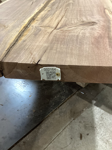 A walnut slab with visible natural crotch wood and pin knots, bearing a QR label.