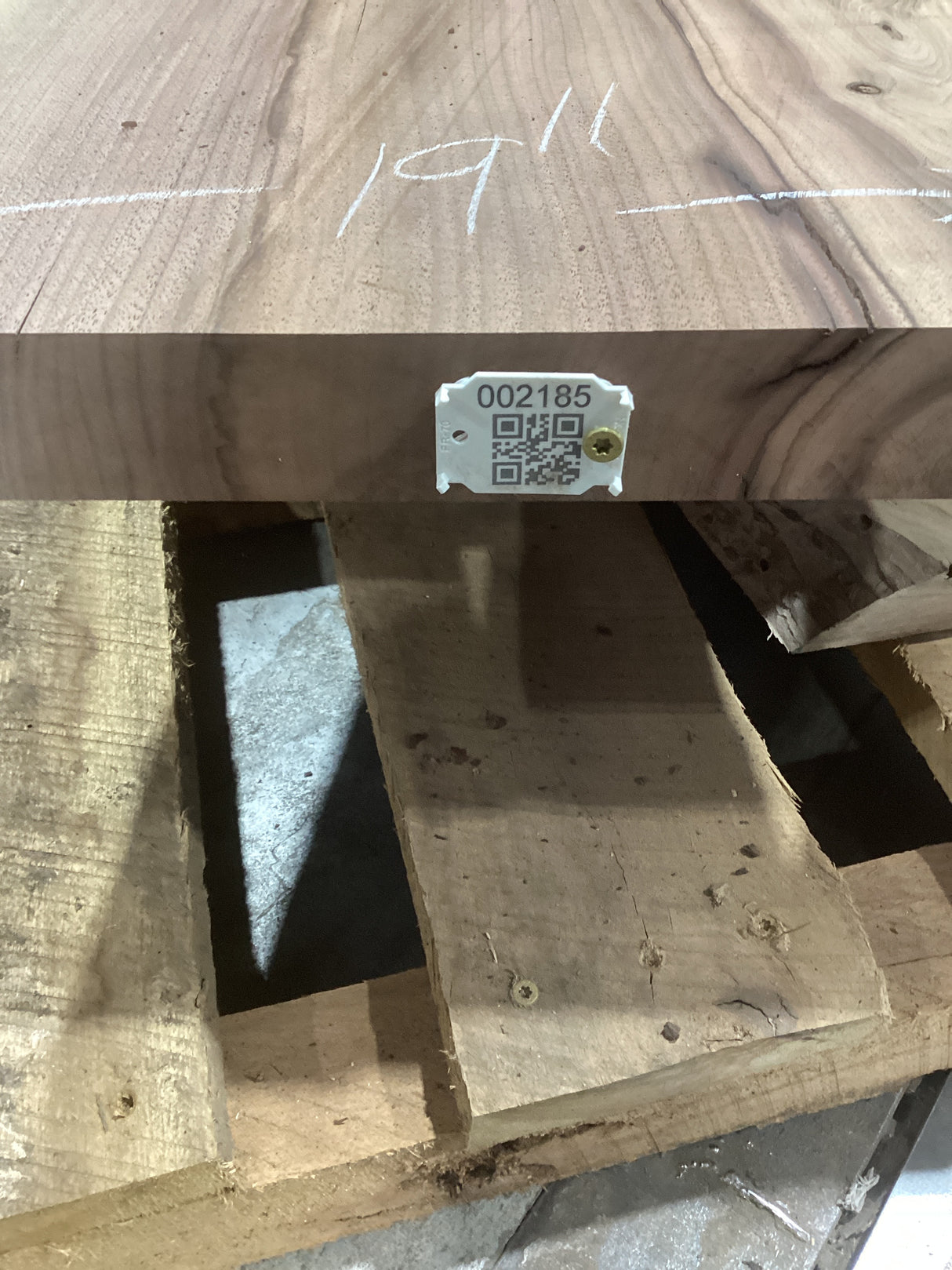 A tapered walnut slab with a visible natural limb hole or void, marked with a QR label on the edge.