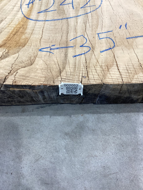 QR label attached to the edge of a red wood slab.