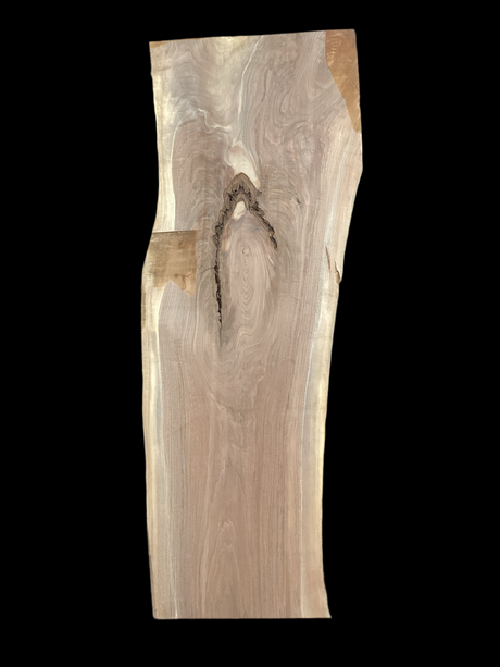 A long walnut slab, wider on one end than the other, and on a black background. 